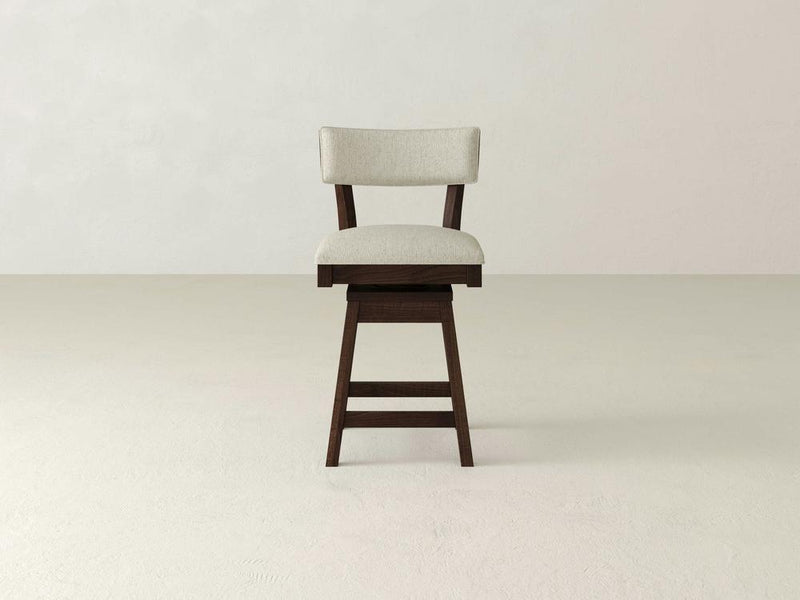 The Everly Swivel Stool by James & James features a dark wooden base and light beige upholstered seat and backrest, set against a plain, light gray background.