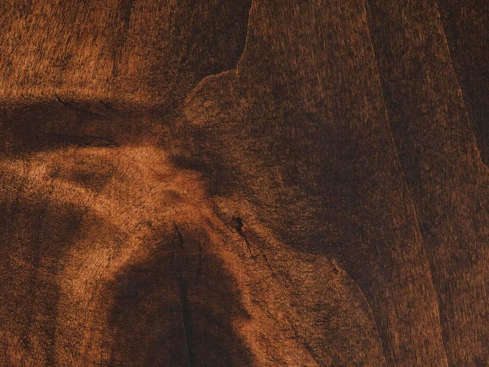 A close-up of the James+James Abigail Coffee Table in Tobacco finish. The rich grain and textured surface display varying shades of brown and unique patterns, emphasizing the natural beauty and intricate details of the wood.