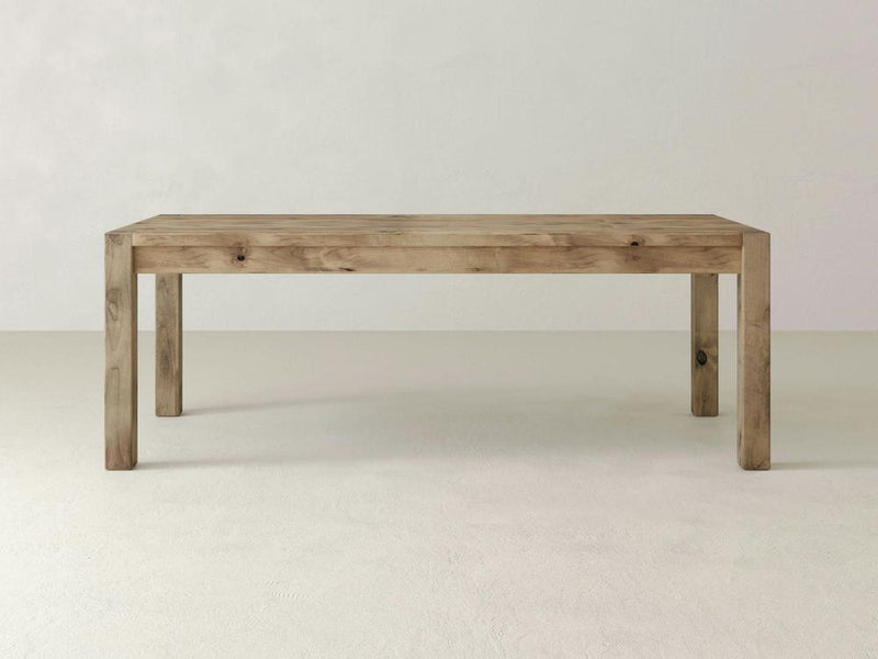 The Jonathan Dining Table - Harvest Wheat by James+James is a minimalist, rectangular wooden table with a light finish. It features a simple design with straight legs and is placed against a plain, light-colored background, highlighting its natural wood grain and clean lines.