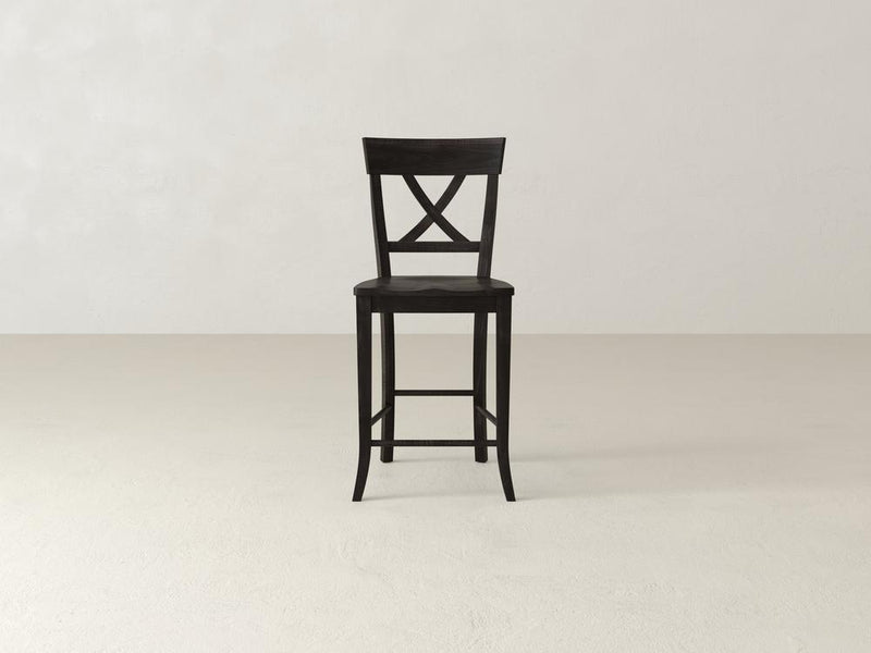 The Juniper Stool by James & James is a tall, dark wooden stool made from maple hardwood, featuring an X-back design and four slender legs, ideal for bar or countertop use.