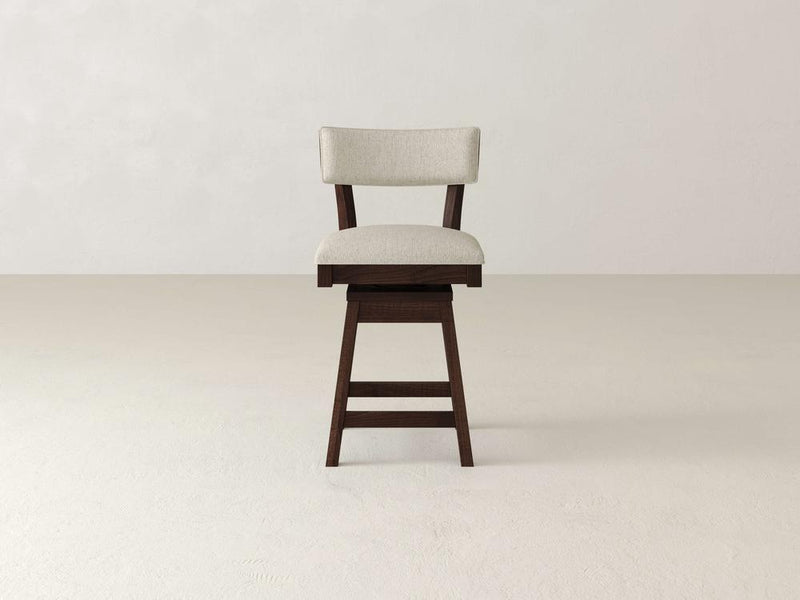 The Everly Swivel Stool by James & James features a wooden frame with cushioned, upholstered seat and backrest in light beige fabric. It showcases a simple mid-century design with a dark brown finish, elegantly set against a plain light gray background.