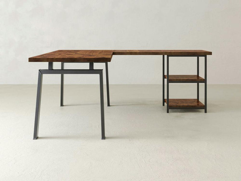 The Fulton Corner Desk - Tuscany by James & James is a modern L-shaped wooden desk with a metal frame, featuring two lower wooden shelves supported by black metal legs, set against a light gray background.