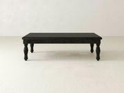 The Abigail Coffee Table in Charred Ember from James+James, a robust piece crafted from dark wood with intricately designed legs, stands on a light-colored floor against a plain white background. The table features a simple, rectangular shape and boasts a smooth, polished surface.