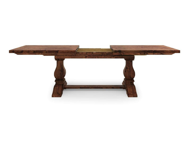 The Heirloom Expandable Dining Table - Tuscany by James+James is a wooden dining table with a dark finish, featuring two rectangular leaves extended on either side. The table has two ornate pedestal legs connected by a horizontal stretcher bar and an extendable central section.