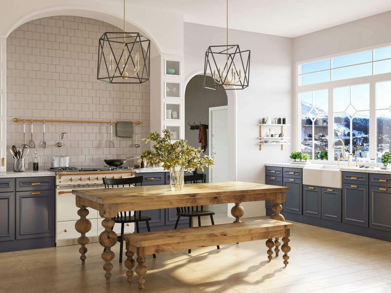 A spacious kitchen boasts a wooden table flanked by the Olivia Bench in Harvest Wheat from James+James, complemented by a vase of flowers. The room features modern lighting fixtures, blue lower cabinets, and white upper cabinets. Large windows flood the space with natural light, offering a stunning mountain view in the background.