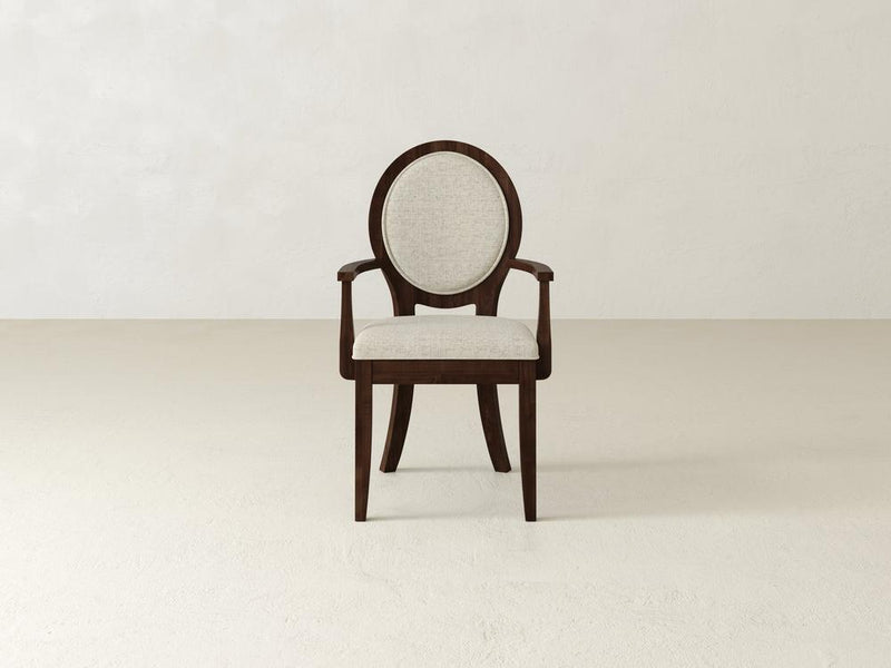 A dark wooden chair with a circular backrest and light gray upholstered seat and backrest is set against a plain off-white background. The chairs design is elegant and minimalistic.