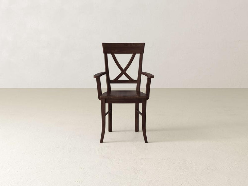 A wooden chair with a dark finish and an X-shaped backrest is centered in an empty room with light-colored walls and floor.