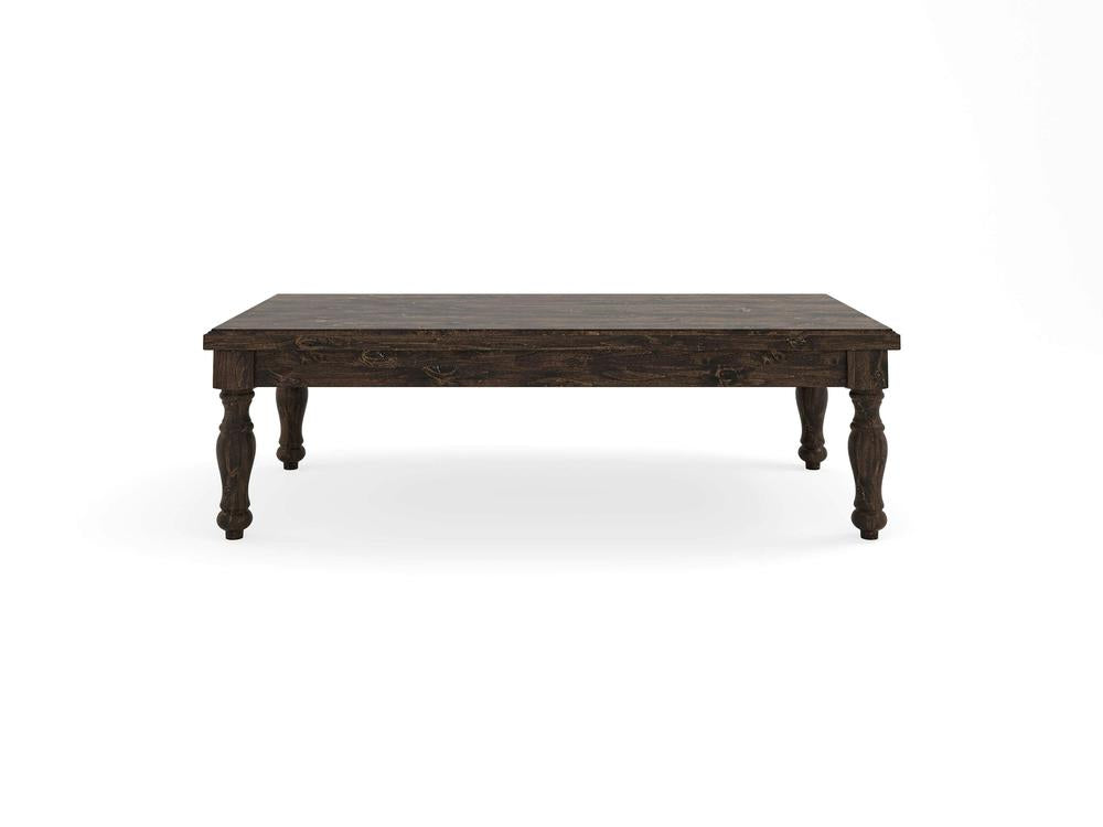 The Abigail Coffee Table - Tobacco by James+James features a rectangular dark wooden top supported by four intricately carved legs, showcasing a rustic, vintage appearance. It is placed against a plain white background.