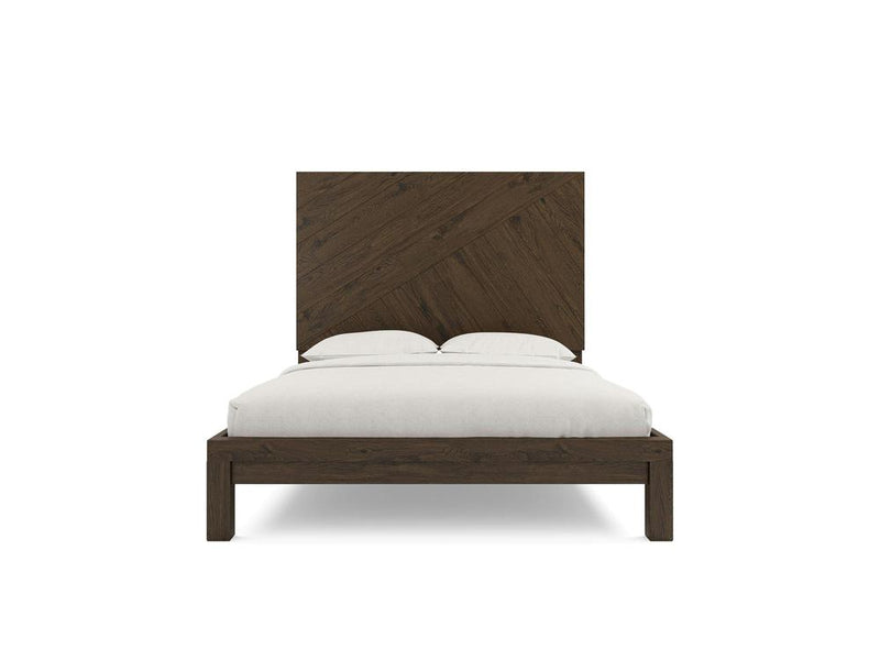A front view of the Luna bed by James+James, showcasing a large, geometric patterned headboard. The wooden frame boasts a dark charred ember finish and minimalist design, while it is fitted with simple white bedding and two pillows.
