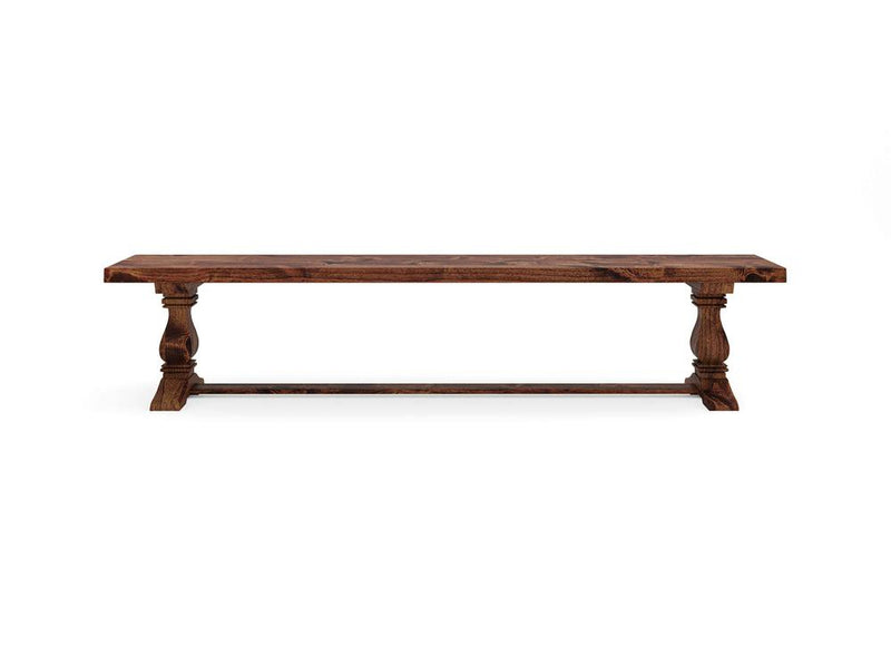 The Heirloom Bench - Tuscany by James+James is a rustic wooden dining table featuring a rectangular top and elegantly carved legs connected by a horizontal support beam at the base, all finished in a warm, natural wood tone.